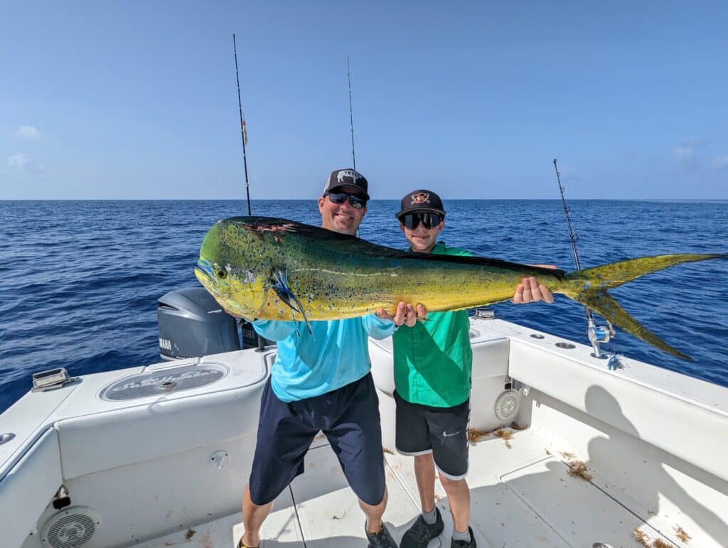 two anglers holding a big bull mahi mahi (aka dolphin or dorado) with Capt Ryan Van Fleet in the Florida Keys