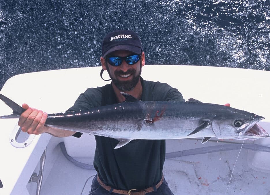 man holding a recently caught king mackerel.