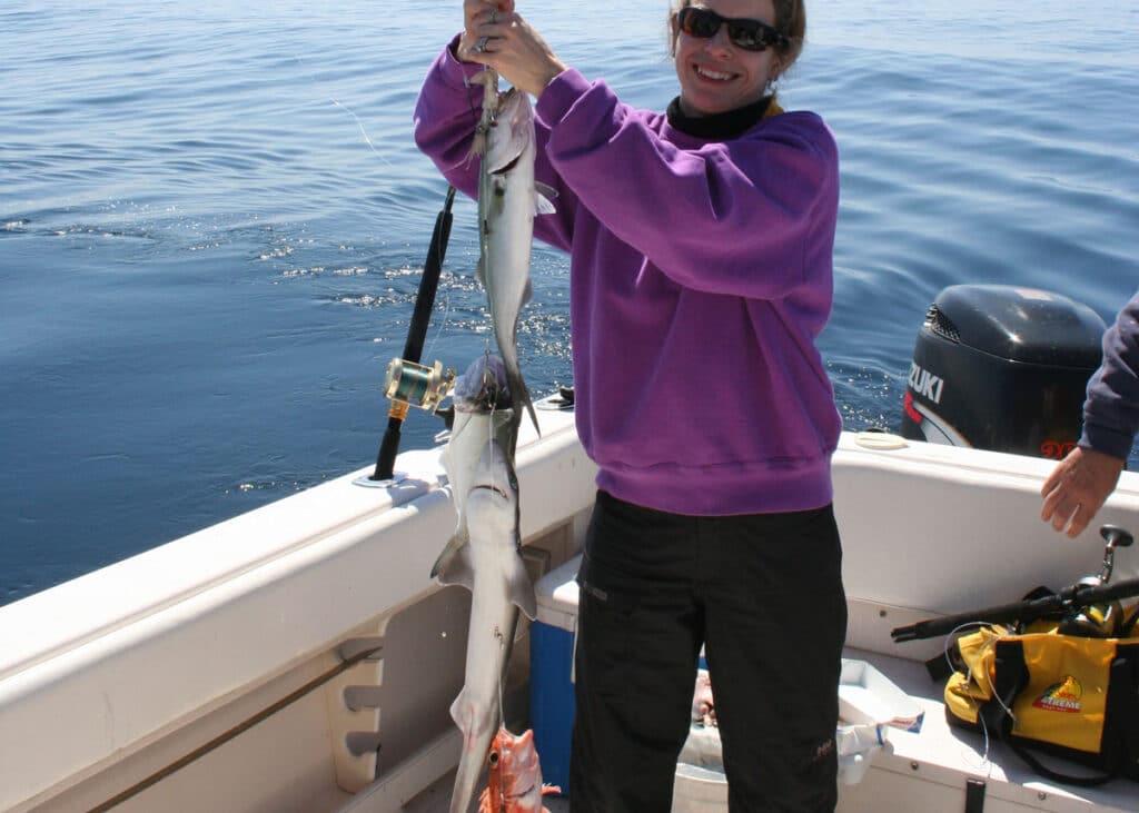 a woman holding up a mix of bluefish, spiny dogfish, and a rosefish